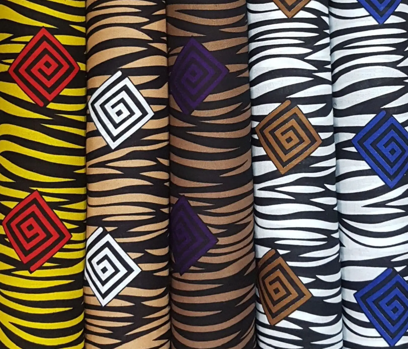 Stripes and Dots17 Collection, all colorways shown together. Bold animal-stripe zigzags run across the cloth, anchored by concentric diamond and spiral medallions that float over the print.