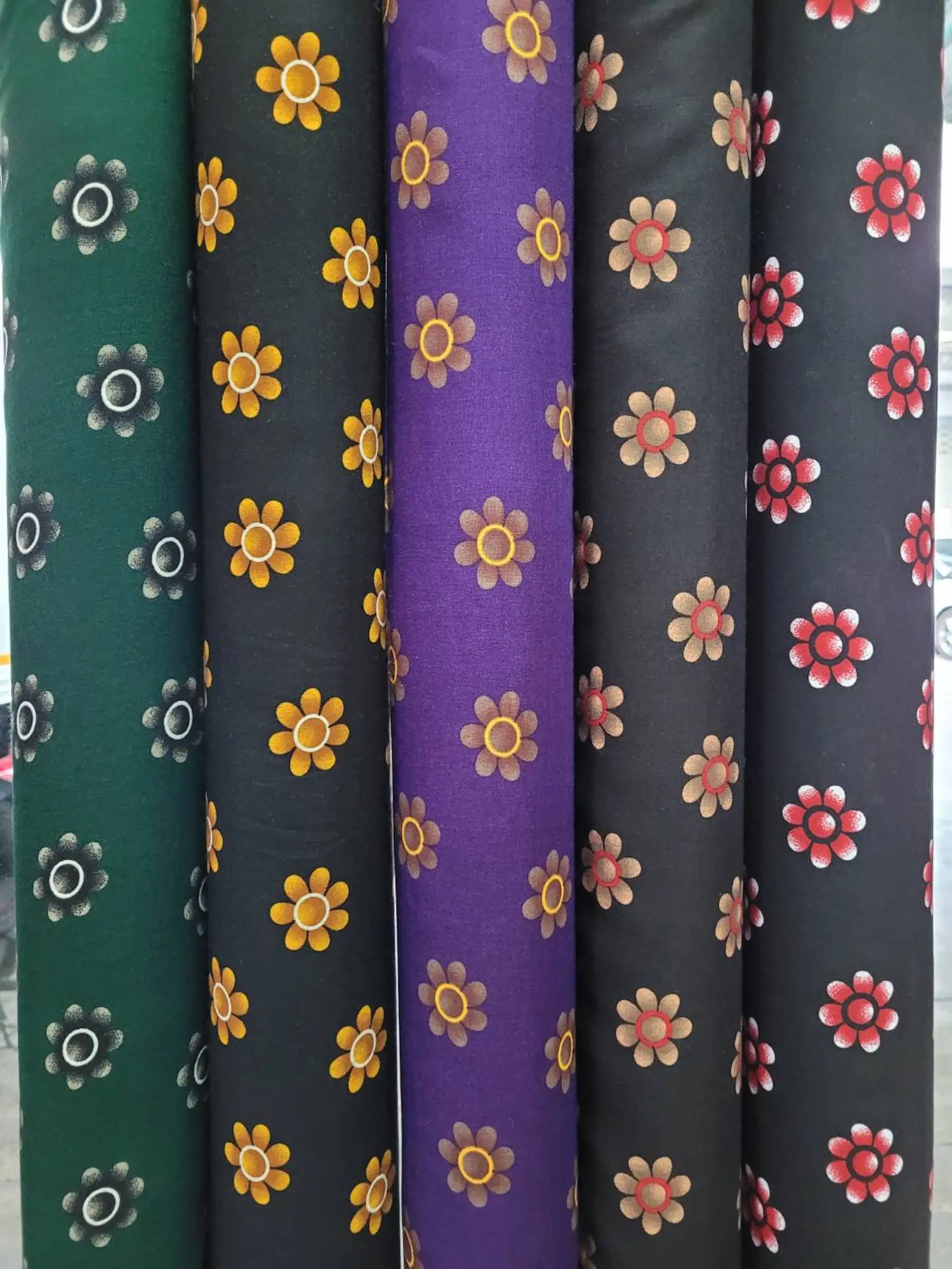 Floral11 Collection, all colorways shown together. Evenly spaced daisy-style flowers with rounded petals and a ringed center repeat in neat diagonal rows.