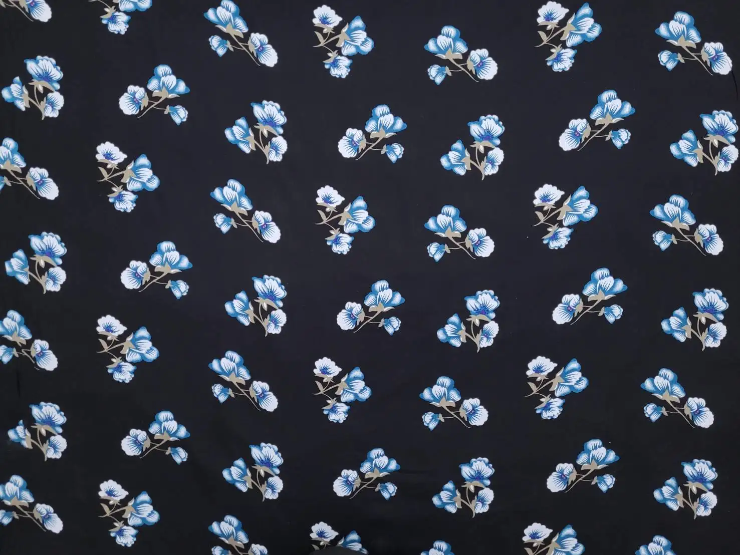 Floral12 Collection in Blue Flower. Charcoal black ground carrying bright sky-blue and teal blooms with tan and gold leafy stems.