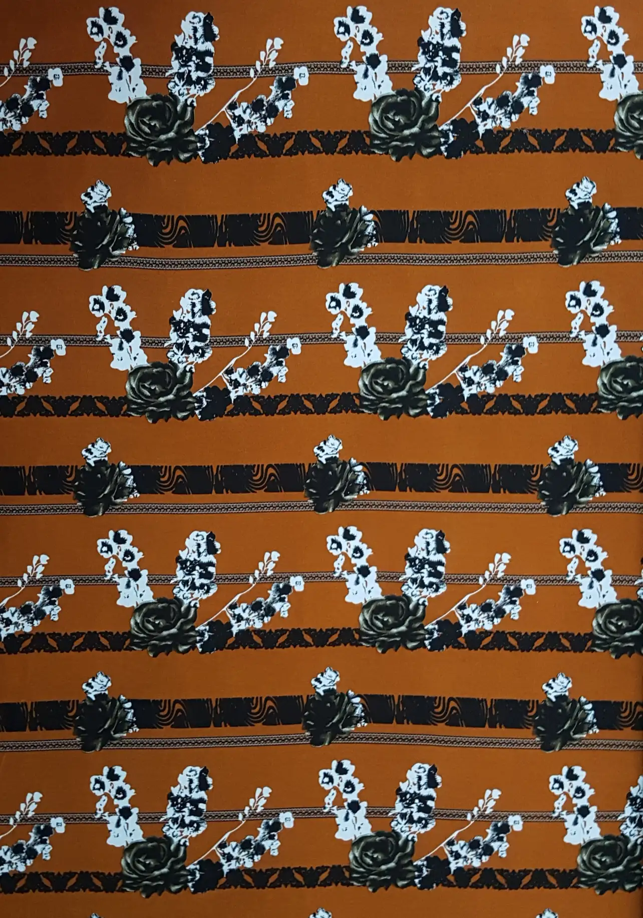 Floral20 Collection in Orange Grey Flowers. Burnt orange ground printed with grey and white floral clusters and black scroll banding.